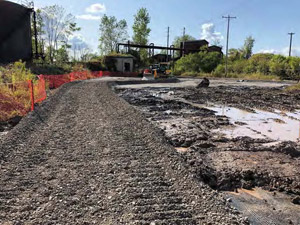 September 2019 - View looking west. Aggregate placed over geogrid and geotextile fabric to construct the access road connection to the ramp and adjacent to the tanks. Wet area to the right of the access road caused by early morning rain event.